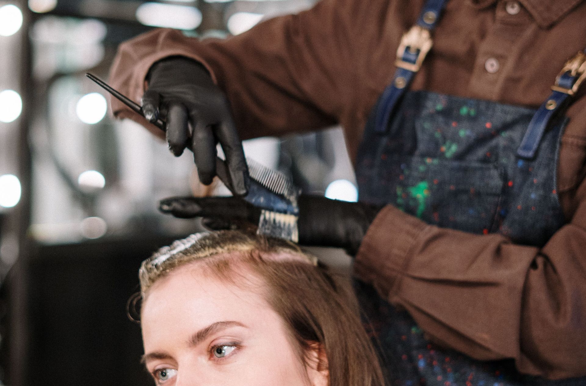 A hairstylist expertly dyes a woman's hair in a contemporary salon setting, highlighting beauty and care.